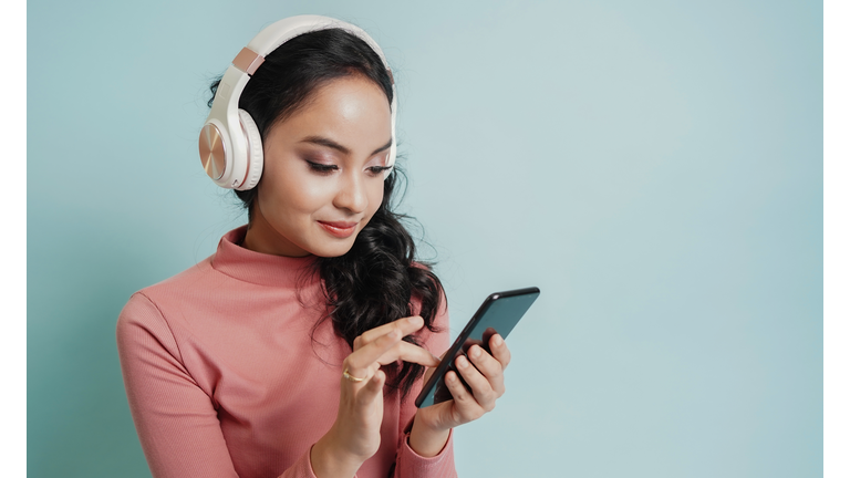 Happy teenage beautiful girl use mobile phone to open the music song from smartphone application. technology concept