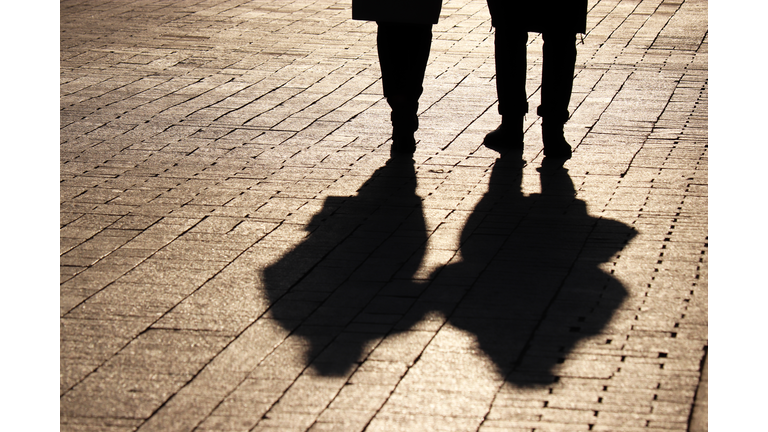 Silhouettes and shadows of couple walking down the street