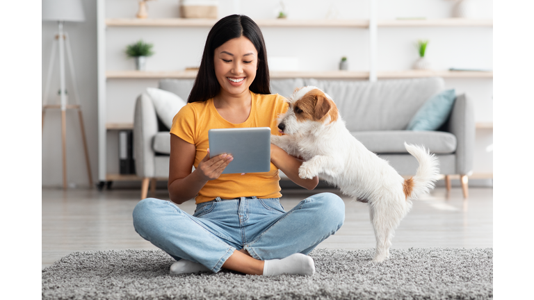 Asian woman and cute dog having fun together at home