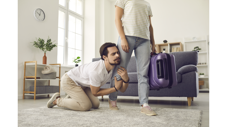 Young married couple breaking up and angry wife leaving home with packed suitcase