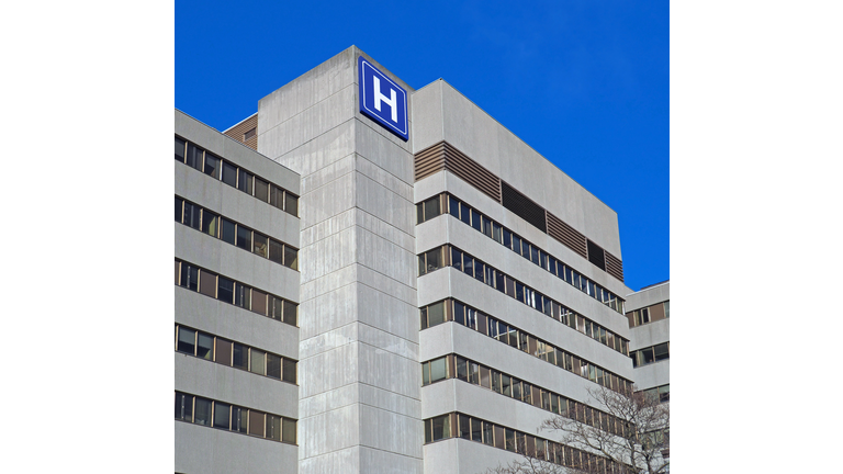 Large concrete building with  H sign for hospital