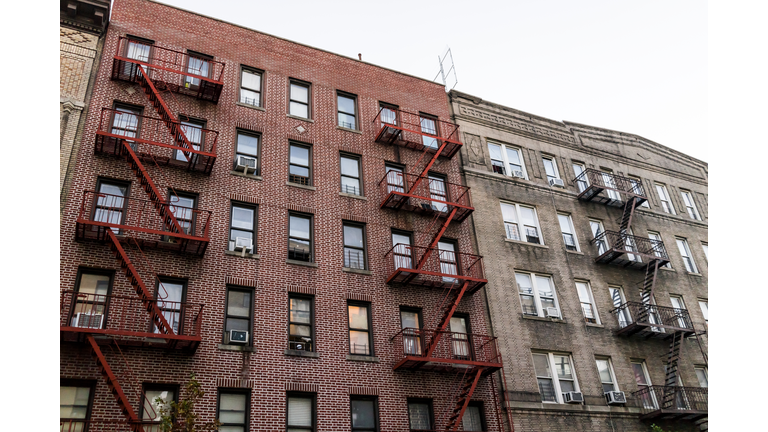 Brick apartment condo building exterior architecture in Fordham Heights center, Bronx, NYC, Manhattan, New York City with fire escapes, windows, ac units in evening