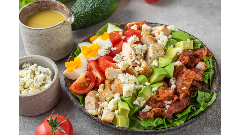 Healthy cobb salad with chicken, avocado, bacon, blue cheese, tomato and eggs on gray background. Keto diet food. close up