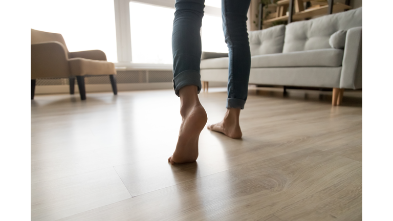 Close up of woman walking barefoot on warm wooden floor