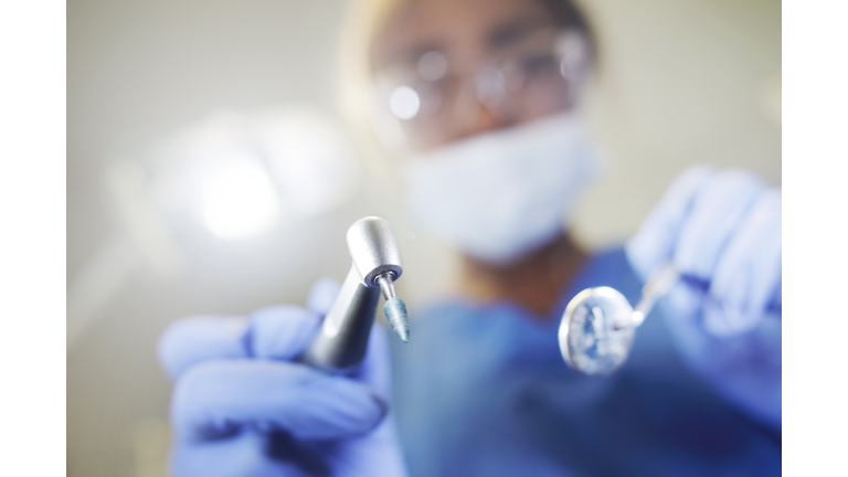 Dentist looking down on camera with tools in hand