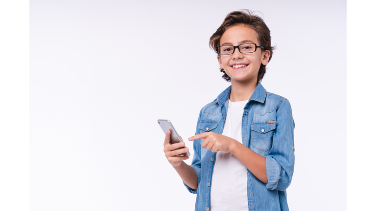 Happy little child pointing at smart phone isolated over white background