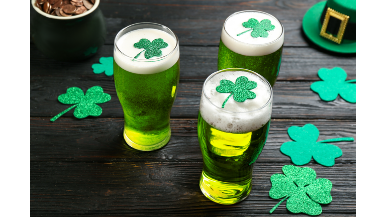 Green beer and clover leaves on black wooden table. St. Patrick's Day celebration