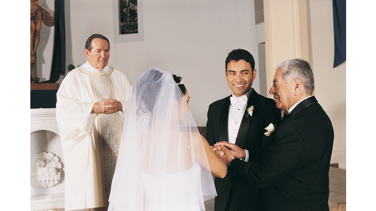 Father of the Bride Gives her Hand in Marriage to the Groom at the Altar