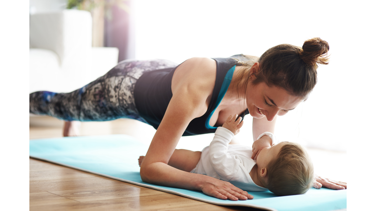 Mother with baby exercising on yoga mat at home
