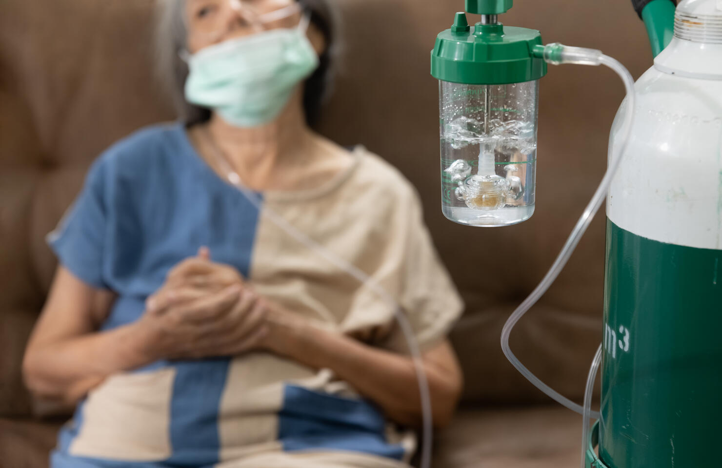 Elderly woman wearing oxygen nasal canula at home.