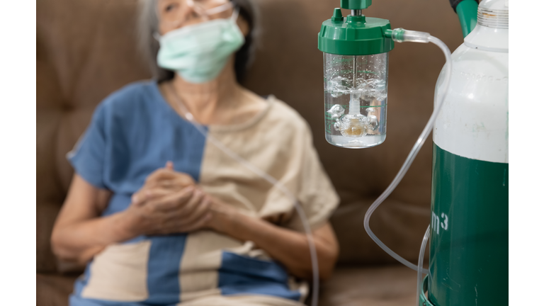 Elderly woman wearing oxygen nasal canula at home.