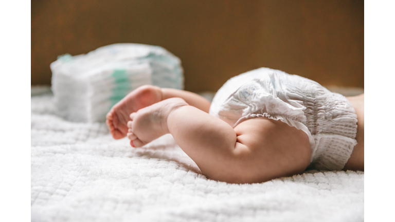 A baby in a diaper at the age of two months and a stack of diapers. How to choose baby diapers