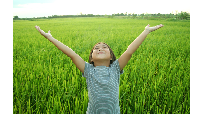 Young girl expressing joy in a field of long grass