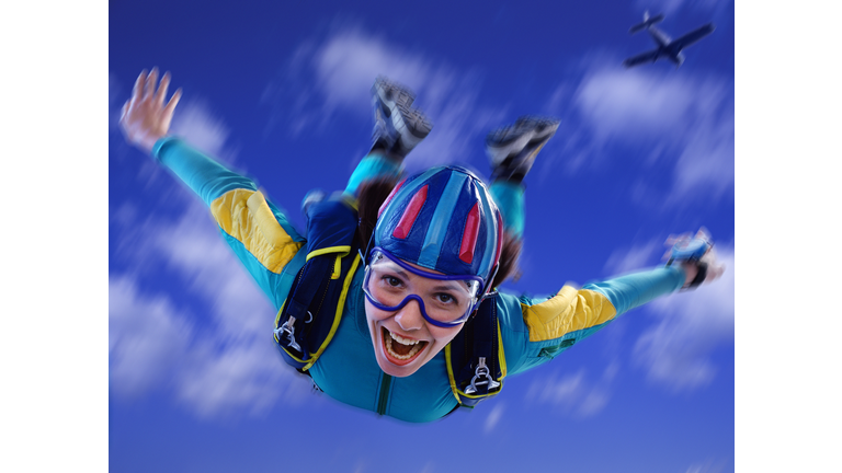 Young woman skydiving, close-up, low angle view (Digital Composite)