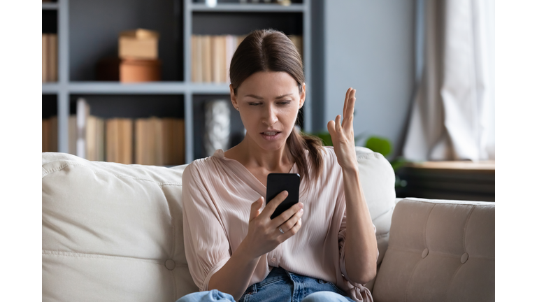 Confused angry young woman having problem with phone