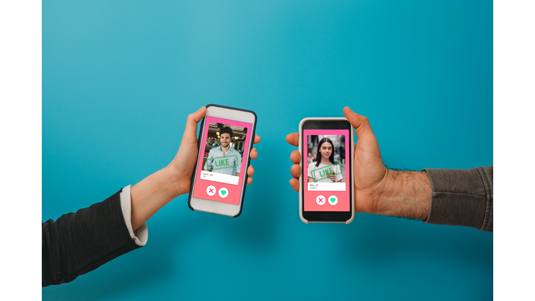 Conceptual image of two hands holding smart phones with an online dating app on the screen
