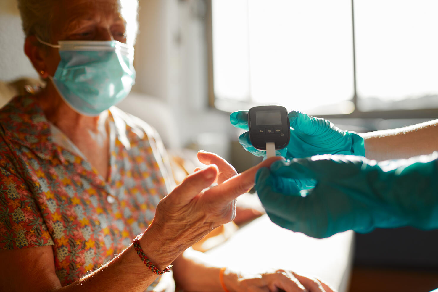 A nurse helping a senior woman perform a diabetes test