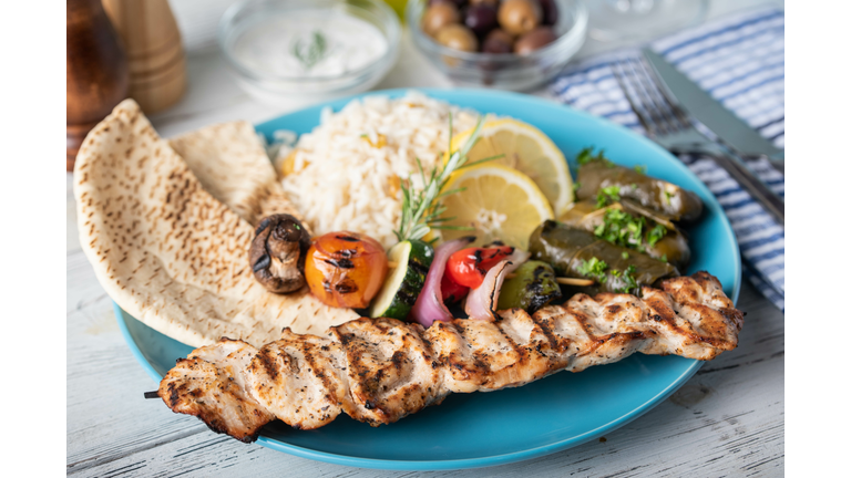 assorted greek food platter with souvlaki, rice, pita and dolmades