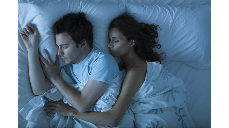 Couple sleeping, woman embracing man