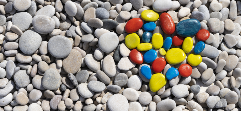 World autism awareness day. Top view to white beach stones with colorful heart made of painted stones
