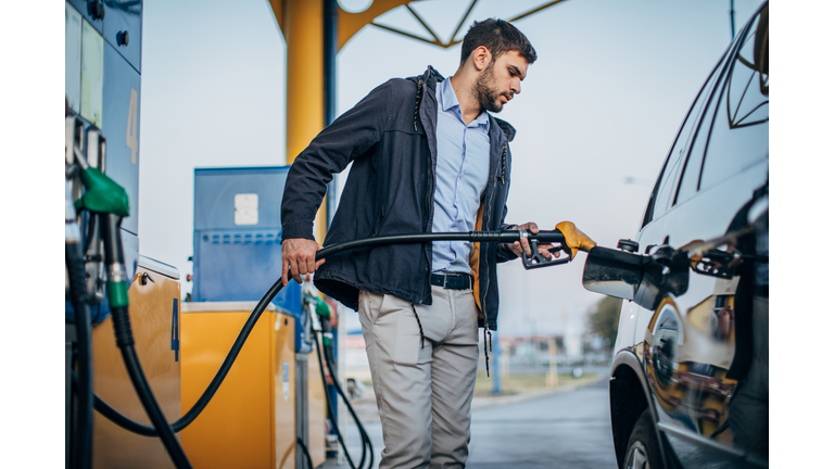 Guy pouring fuel in vehicle at the gas station