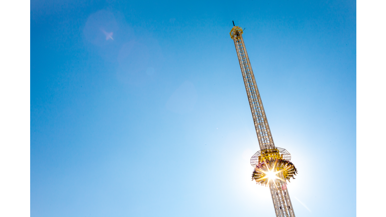 Thrill Ride. Yellow Free Fall Tower And Blue Sky