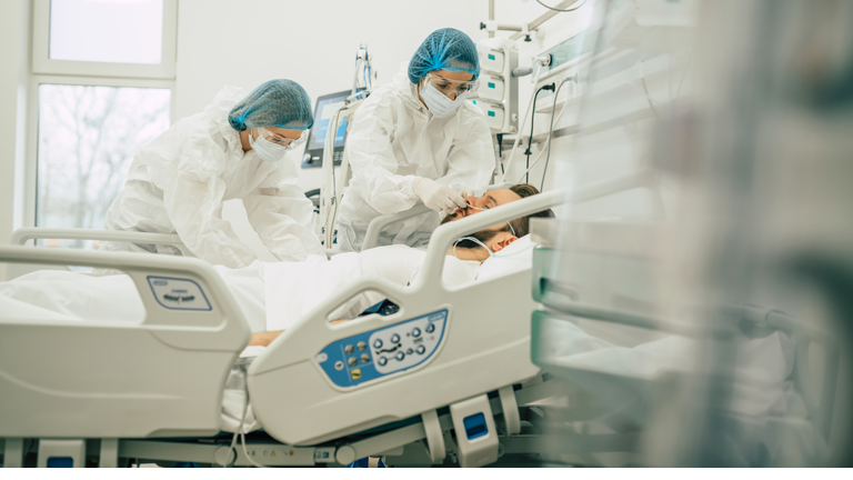 Coronavirus covid-19 infected patient in a quarantine ward at the hospital with doctors in protective suits while they making disease treatment of him