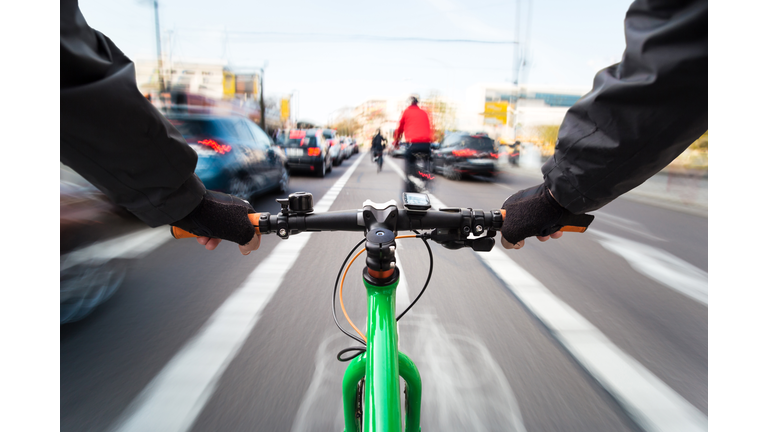 Cyclist drives on the bike path past the traffic jam - First-person view of cyclist/ motion blur