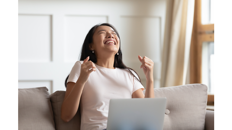Asian woman received news by email on computer feels overjoyed