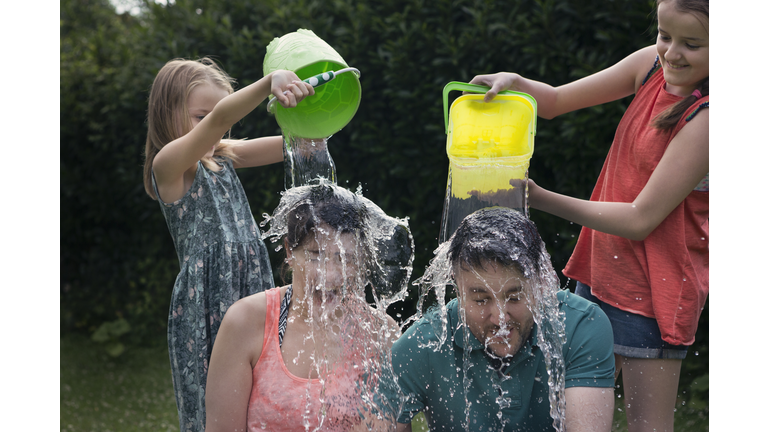 Children throwing buckets of water over adults