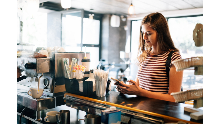 Millennial woman at paying Coffee shop counter