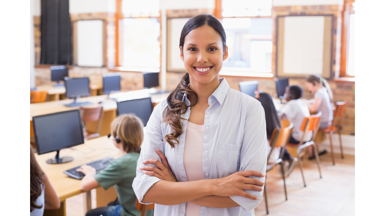 Young pretty teacher standing in a computer room