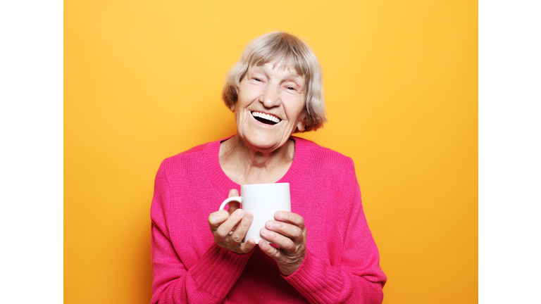 Portrait of old excited lady smiling laughing, holding cup drinking coffee, tea