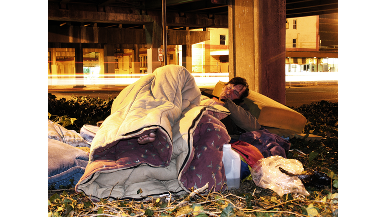 Homeless Man Falling Asleep by the Road