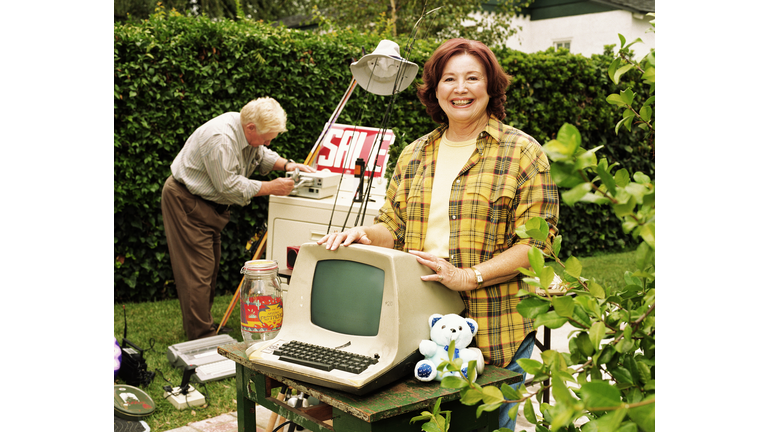 Mature woman standing by old computer monitor at yard sale