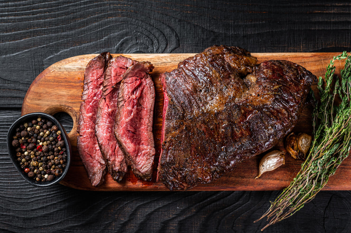 Grilled Butchers choice steak Onglet Hanging Tender beef meat on a cutting board. Black wooden background. Top View