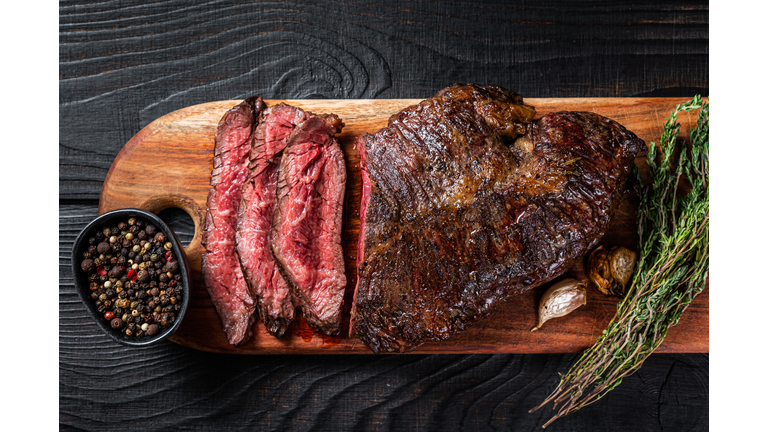 Grilled Butchers choice steak Onglet Hanging Tender beef meat on a cutting board. Black wooden background. Top View