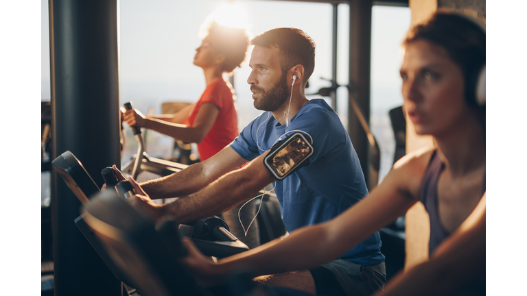 Athletic man listening music while exercising on exercising class in a gym.