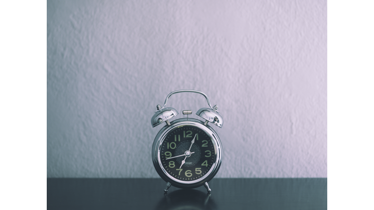 Silver alarm clock on a bedside table.