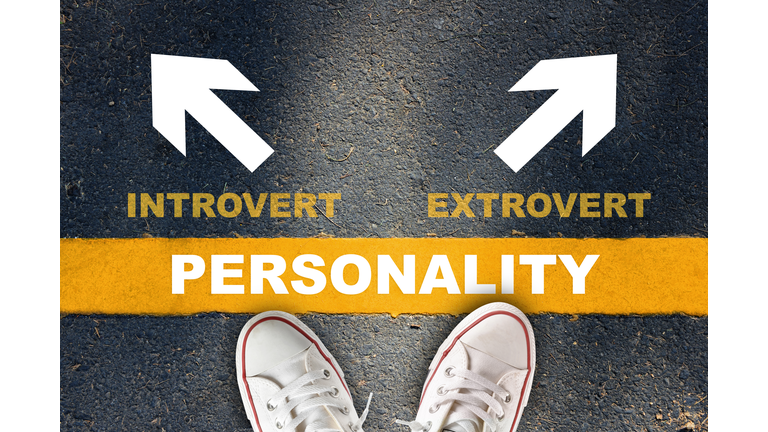 Personality written on yellow line with introvert and extrovert with white arrow on asphalt road