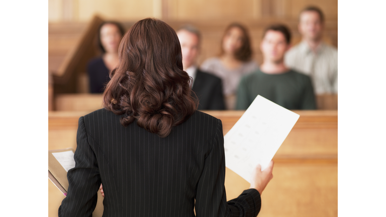 Lawyer holding document and speaking to jury in courtroom