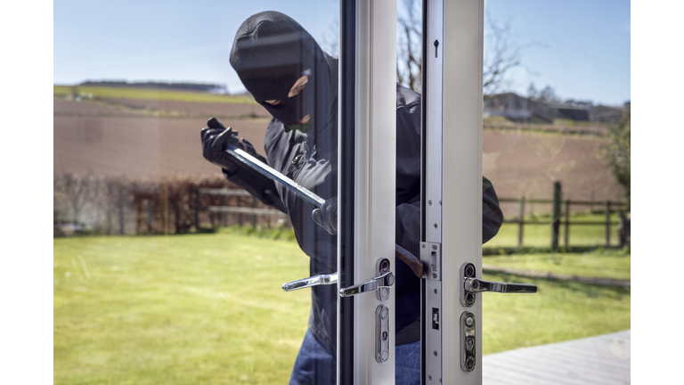 Burglar breaking into a house via a window with a crowbar