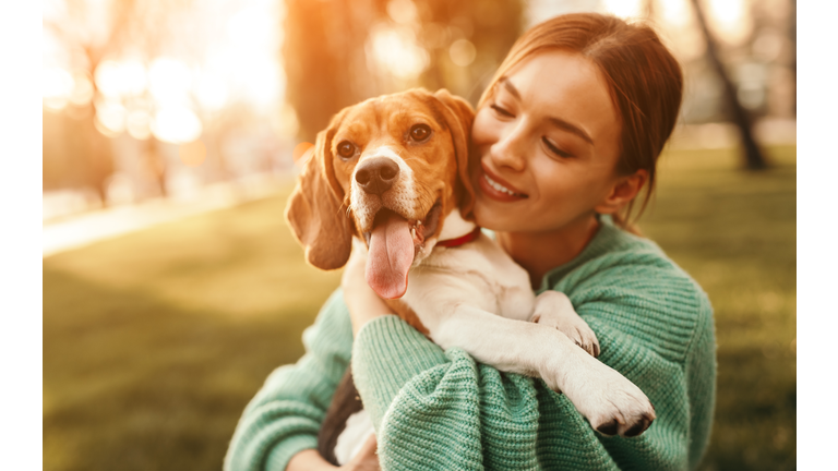 Happy woman embracing beagle dog in park