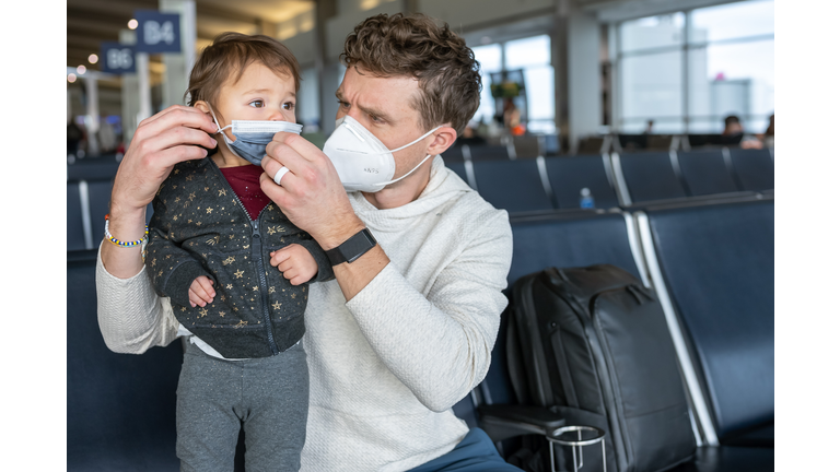 Dad helping daughter put on face mask at the airport