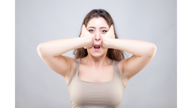 Beautiful young caucasian woman doing face yoga pose