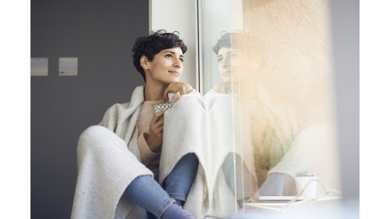 Relaxed woman at home sitting at the window