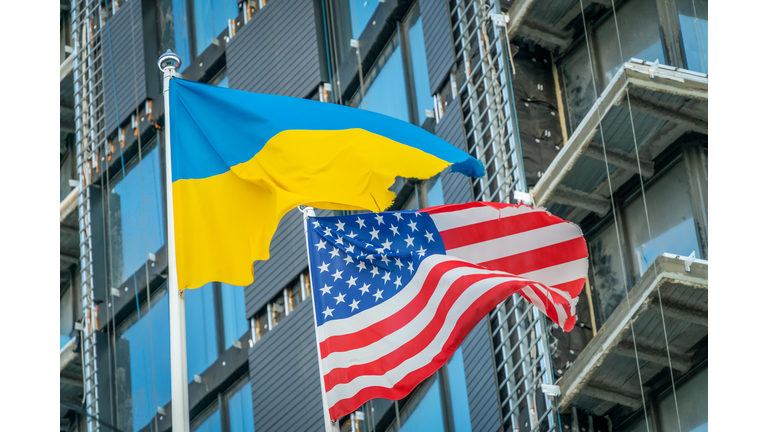 American and Ukrainian flags fly against the blue sky and part of the building. Patriotism.