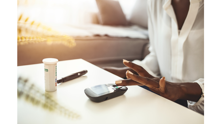 Close up of woman hands using lancet on finger to check blood sugar level