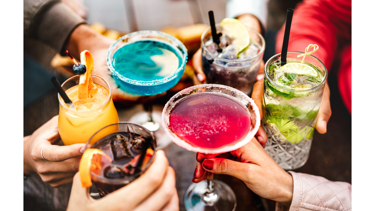 People hands toasting multicolored fancy drinks - Young friends having fun together drinking cocktails at happy hour - Social gathering party time concept on warm vivid filter