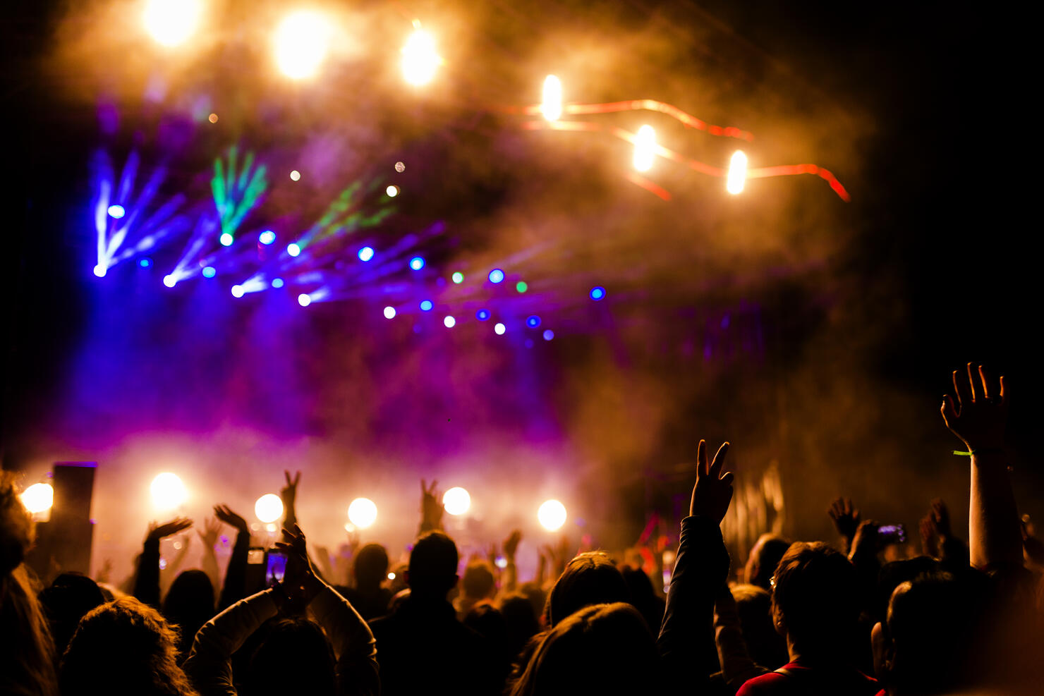 Picture of a lot of people enjoying night perfomance, large unrecognizable crowd dancing with raised up hands and mobile phones on concert. nightlife